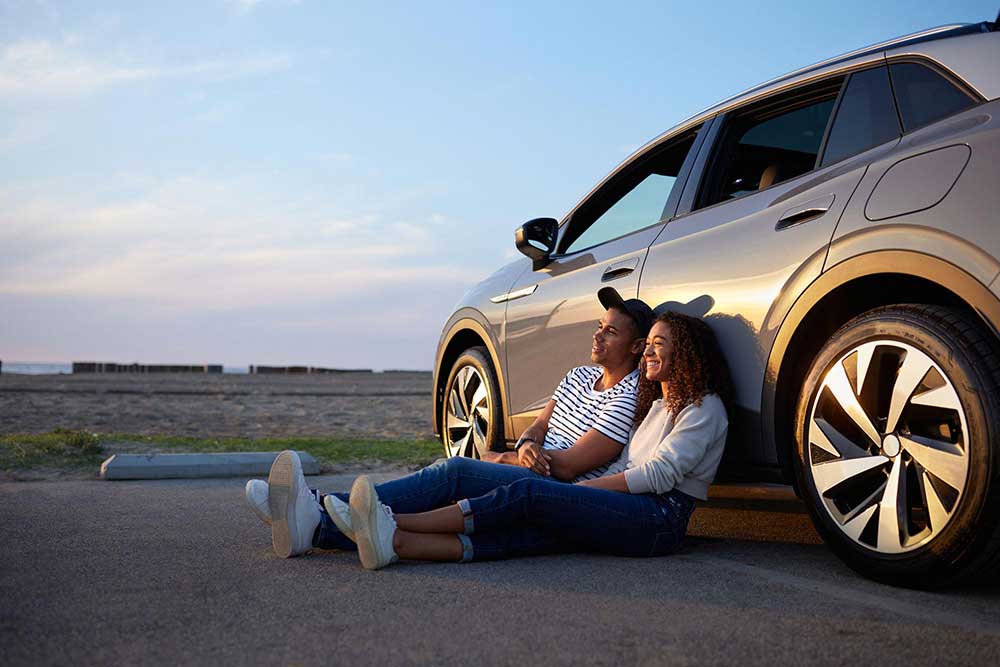 A man and a woman sitting beside a car